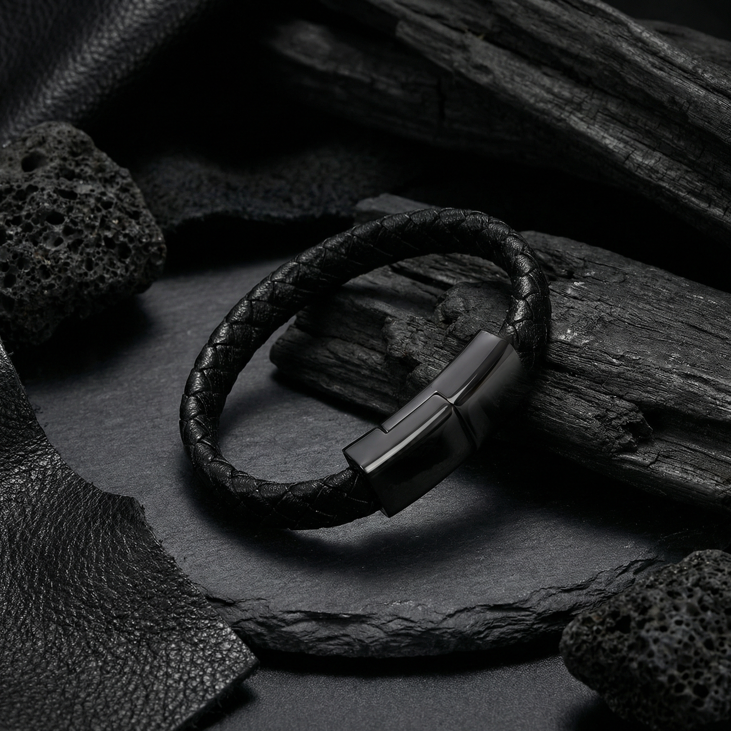 Black leather charging bracelet with metal clasp on a dark stone surface