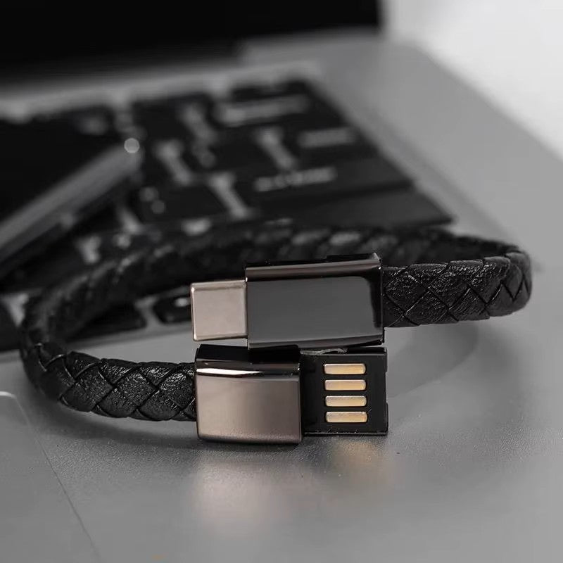 Black braided USB cable bracelet with metallic connectors on a laptop keyboard