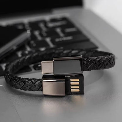 Black braided USB cable bracelet with metallic connectors on a laptop keyboard