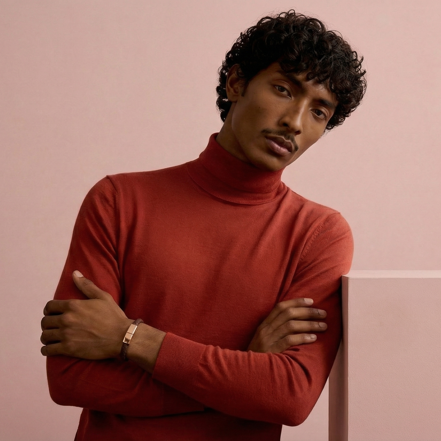 Man wearing a red turtleneck sweater against a pink background