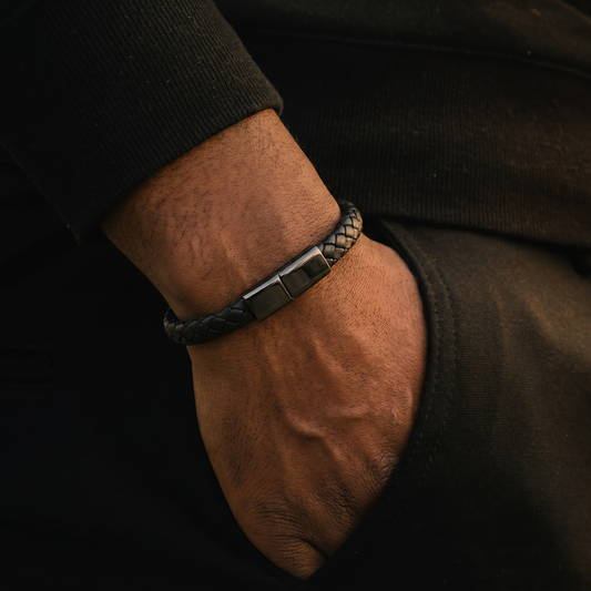 Close-up of a wrist wearing a black leather charging bracelet against a dark background