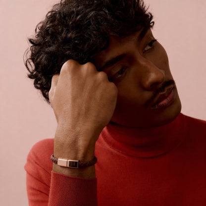 Man wearing a red sweater with a wristband on a pink background