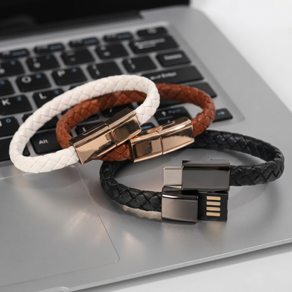 Three braided charging bracelets with metal clasps on a laptop keyboard, showing USB connectors.